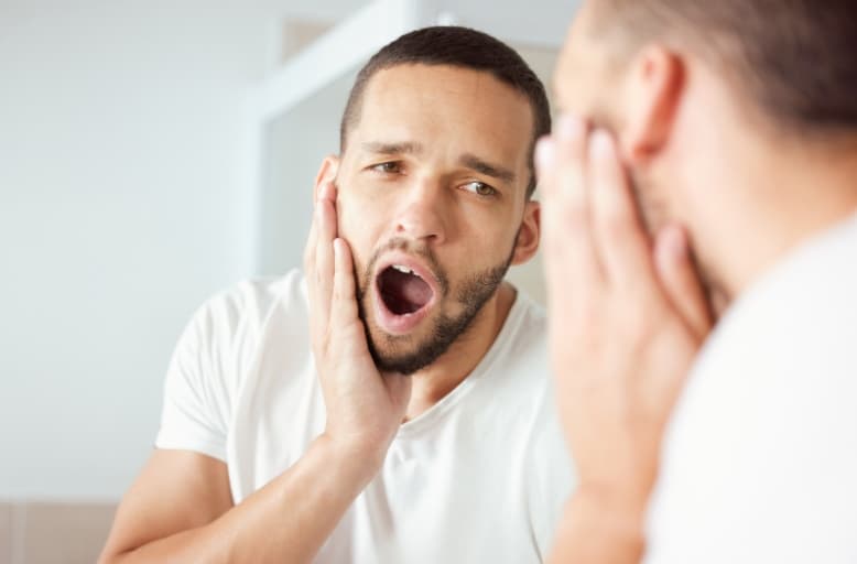 Man holding jaw in pain before tooth extraction treatment in Tomball